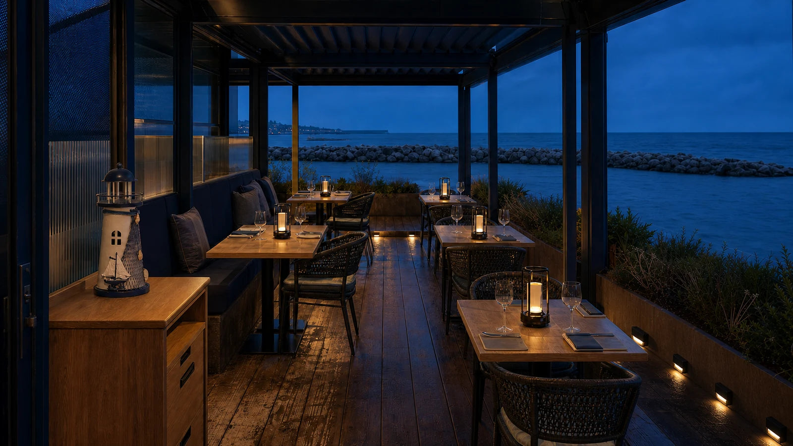 A restaurant terrace at blue hour with layered perimeter and table lighting