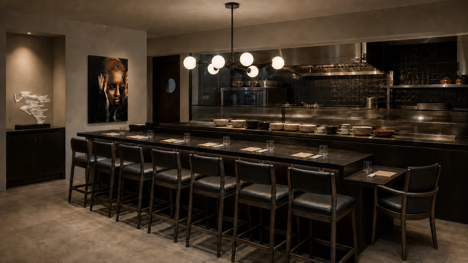 A dark chef's counter with focused warm light on the pass and seated covers